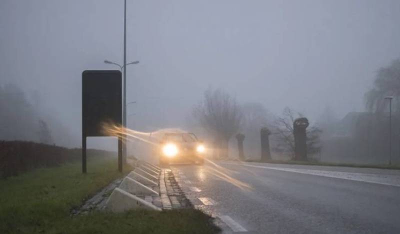 Car driving with headlights on in heavy fog